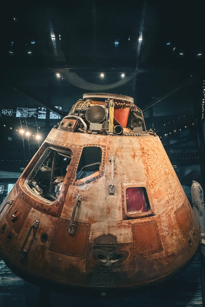 Apollo command module on display in a Washington DC museum showing the worn exterior and small windows from its return from space.