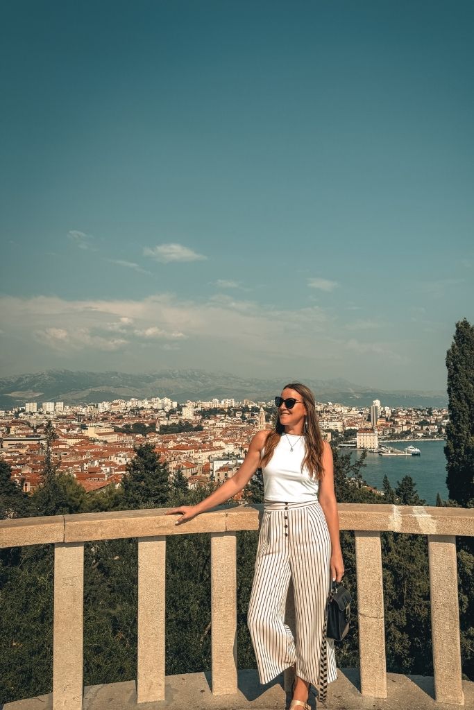 Kate standing on a terrace overlooking the city of Split, Croatia and its marina. 