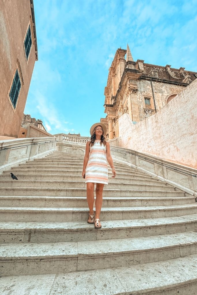 Kate walking down the Jesuit Stairs, smiling in a summer dress.
