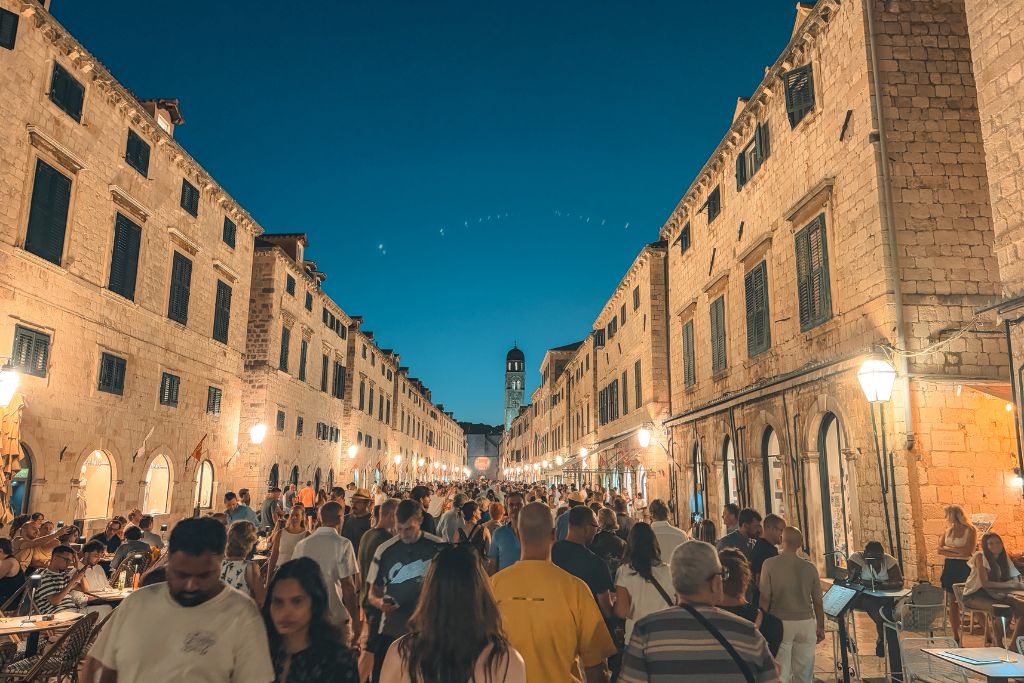 The main street in Dubrovnik Croatia at night that is packed with tourists shoulder to shoulder. 