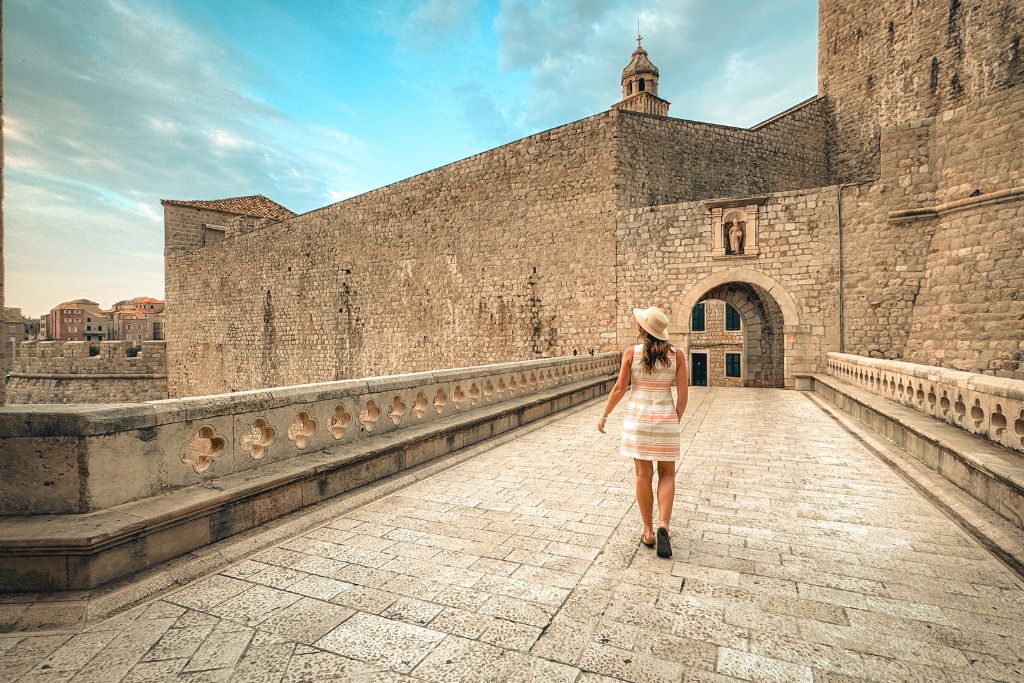 Kate walking across the stone bridge and gate entrance to Dubrovnik's walled city.