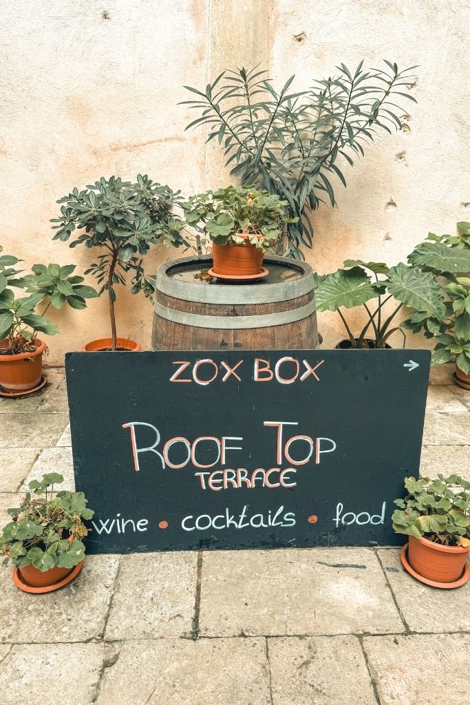 A black sign that says Zox Box, Roof Top Terrace, wine, cocktails, food.