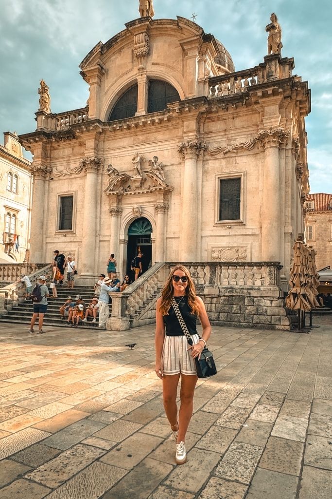 Kate stands in front of an old church, smiling.