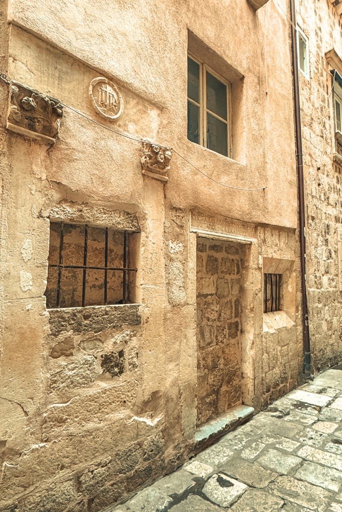 A old door and window that has been closed with stone and mortar on a narrow street in Dubrovnik.