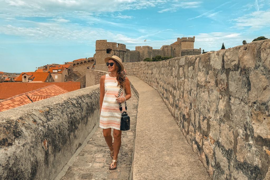 Kate walking on top of the walls of Dubrovnik with the red roof tops in the background. 