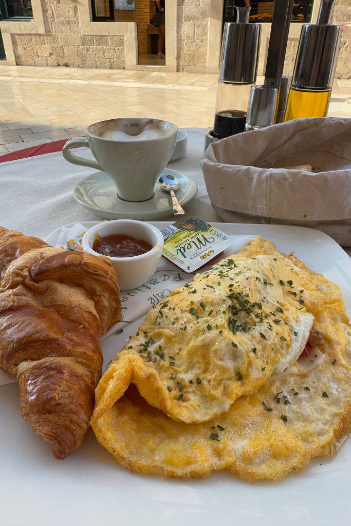 A breakfast plate with a croissant and an omelet. 