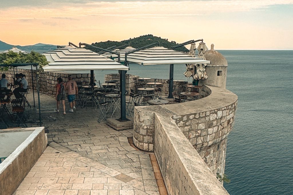 Small cafe on top of the Wall in Dubrovnik set up with tables and umbrellas.