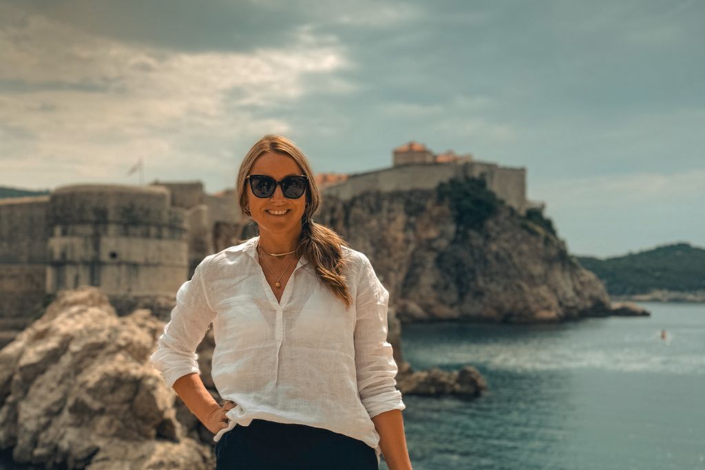 Kate posing for a photo with Dubrovnik and its walls in the distance.