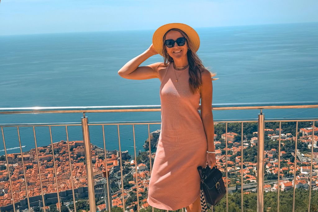 Kate standing next to a railing that overlooks the city of Dubrovnik and the Adriatic Sea below