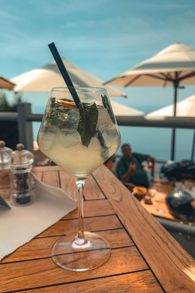 A Hugo spritz on a table with a sea view on a sunny day. 