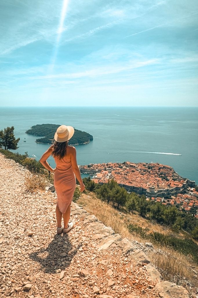 Kate stands on a trail above Dubrovnik looking down at the city.