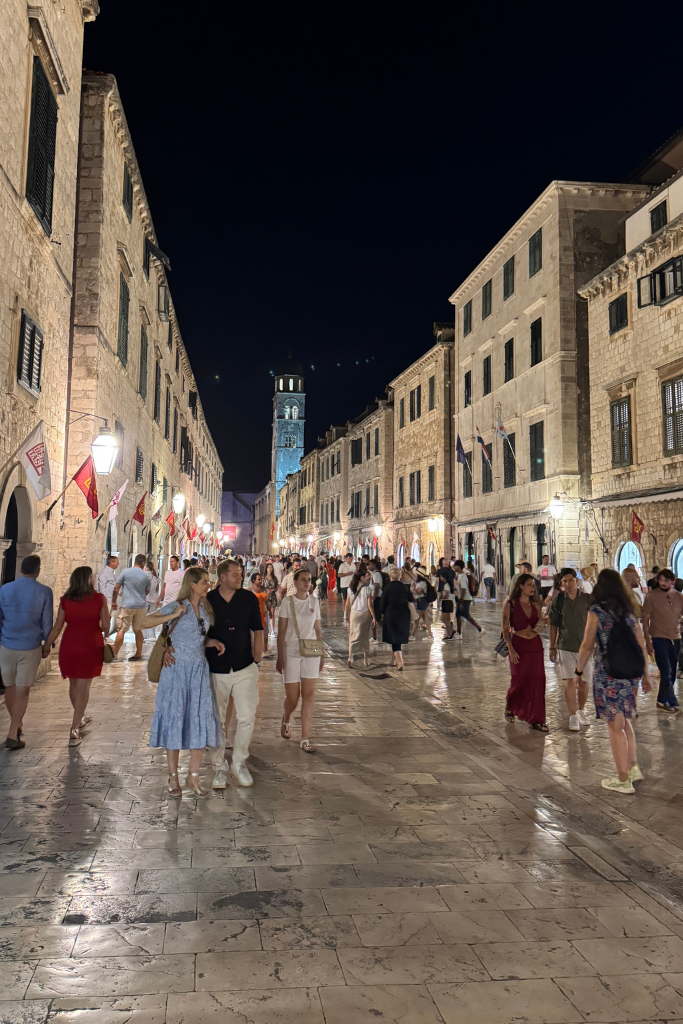People walking Stratum Street at night with lanterns lit under a dark sky.