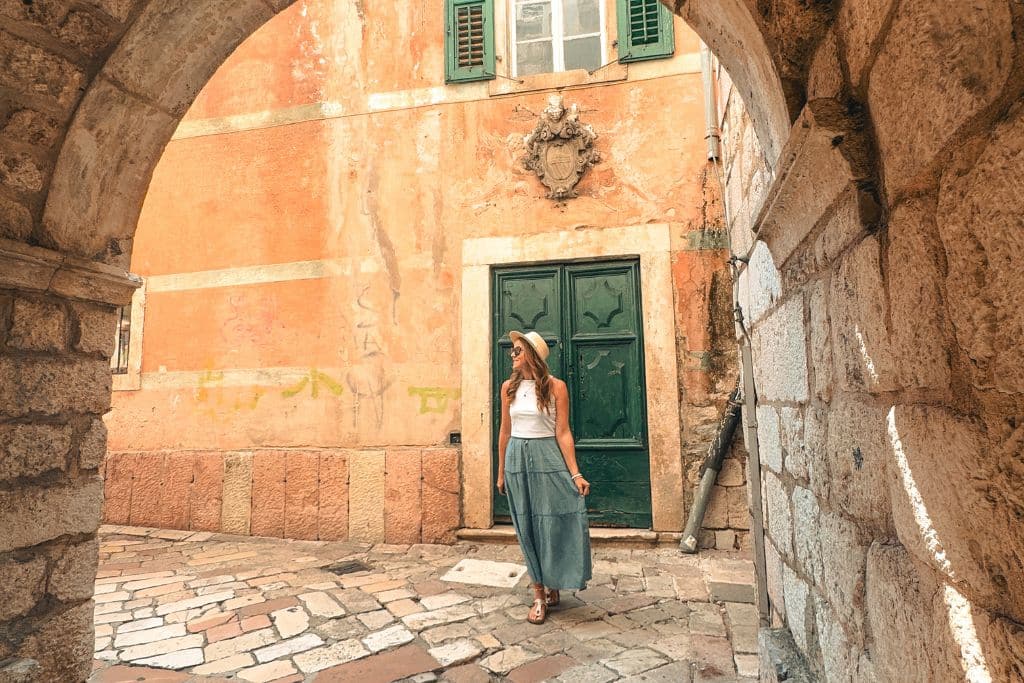 Kate wanders through the charming stone alleyways of Kotor Old Town, surrounded by historic architecture and the warm Mediterranean atmosphere of Montenegro.