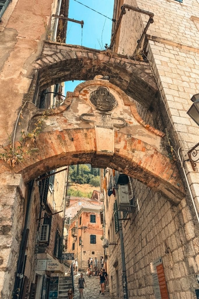 A charming stone archway connects the historic alleyways of Kotor Old Town, showcasing the layered medieval architecture and timeless atmosphere of Montenegro.