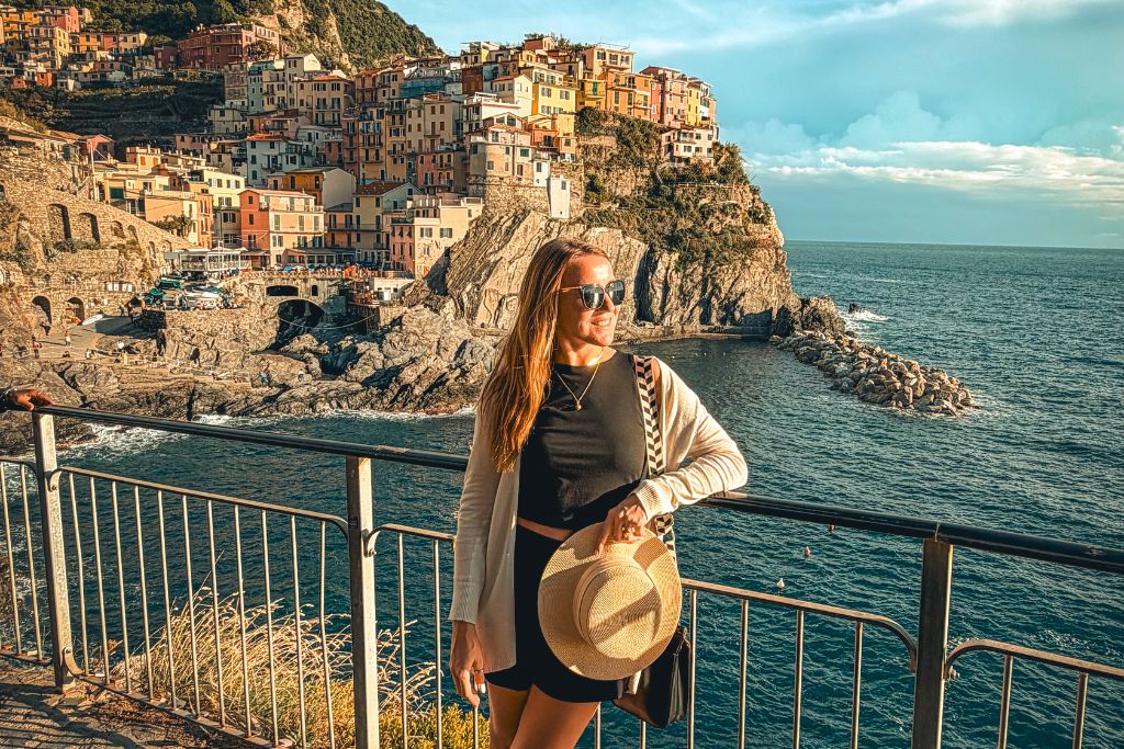 Kate wearing a simple black matching set, lightweight cardigan, and comfortable sandals while exploring Europe’s stunning coastline as the sun sets.