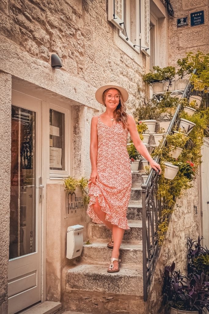 Kate in a flowy floral dress, comfortable sandals, and a wide brim hat create the perfect lightweight outfit for wandering Europe’s charming streets in summer