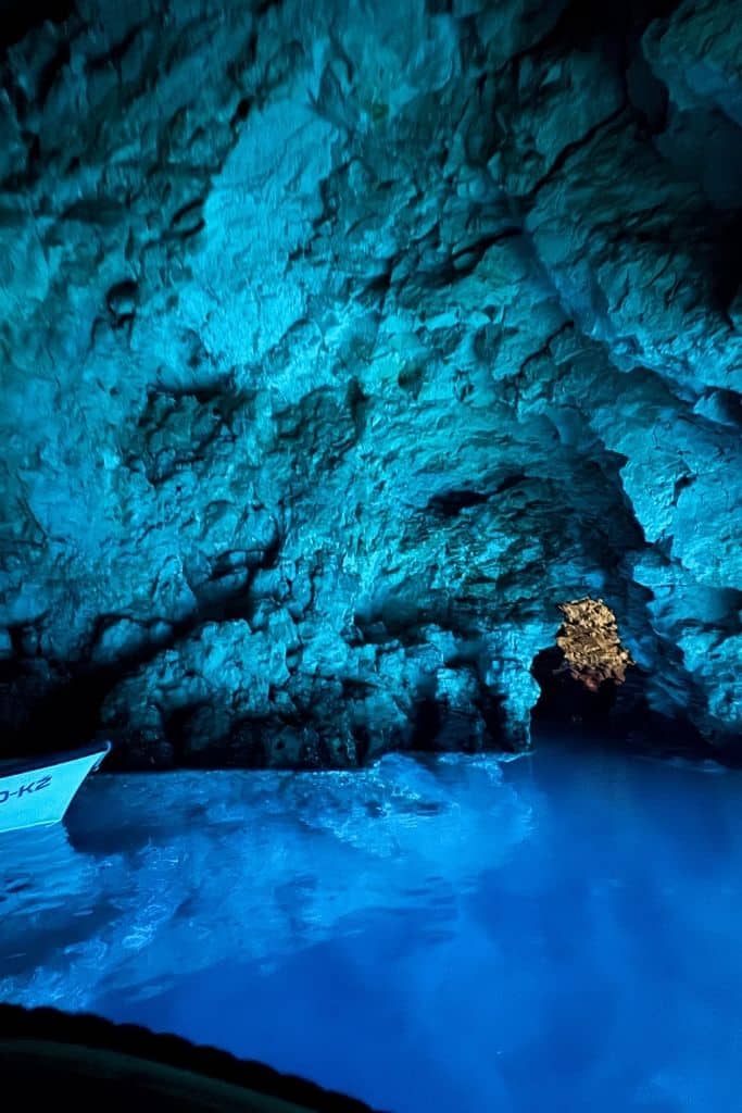 The inside of a cave glowing blue from the reflection off of the blue water within.