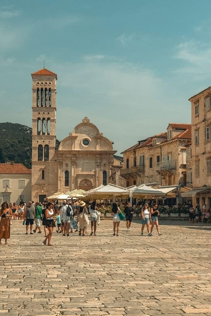 People wandering St. Stephen’s Square on a sunny afternoon in Hvar Croatia.