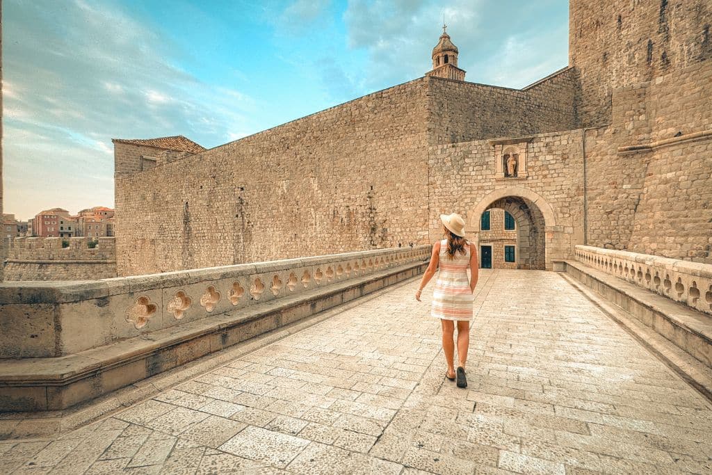 Kate walking alone across a bridge, entering the walled city of Dubrovnik Croatia.