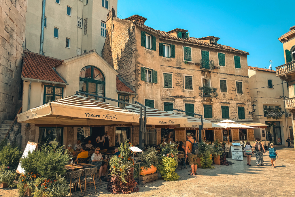 A restaurant with an outside pattio filled with tables, plants and sun shades in the Old Town of Split.