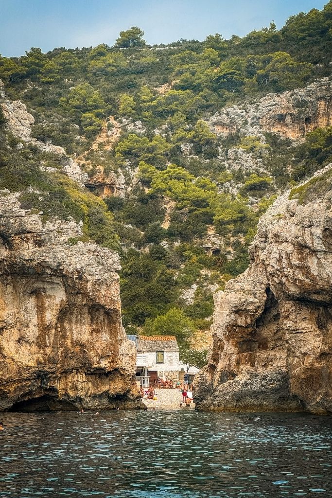 View of a small beach between two huge cliffs from a boat.