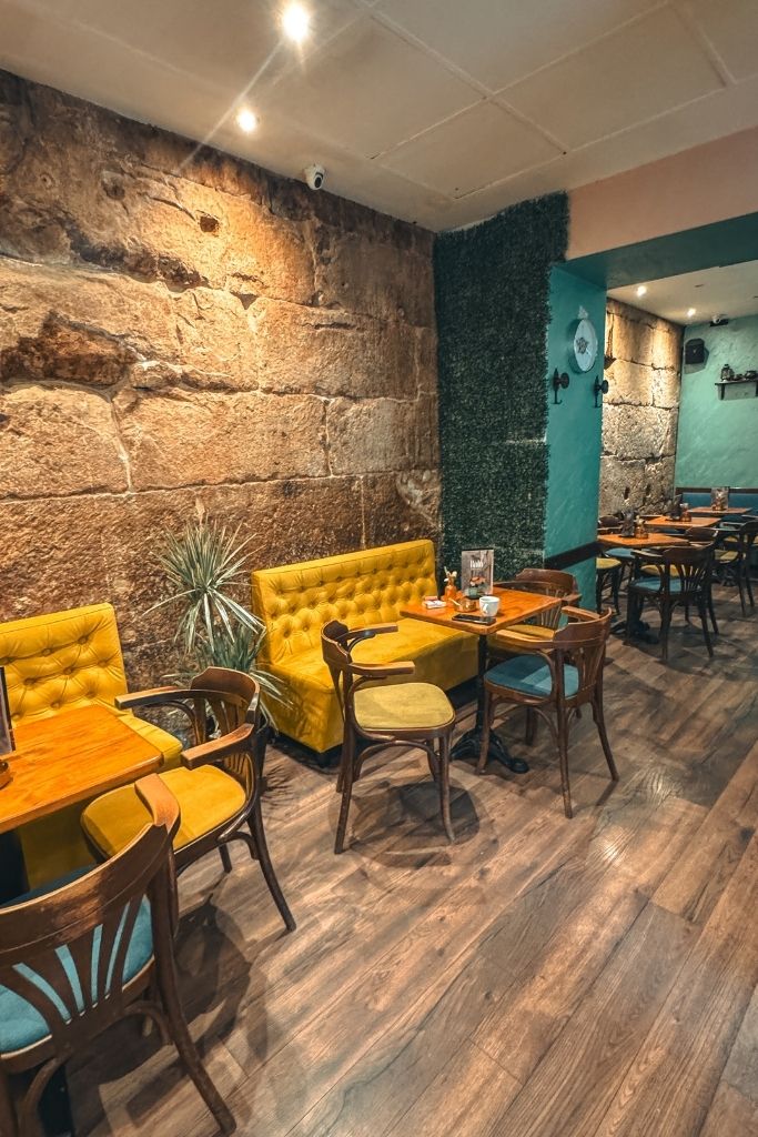Inside the Cafe with natural stone walls and yellow couches and turquoise chairs.