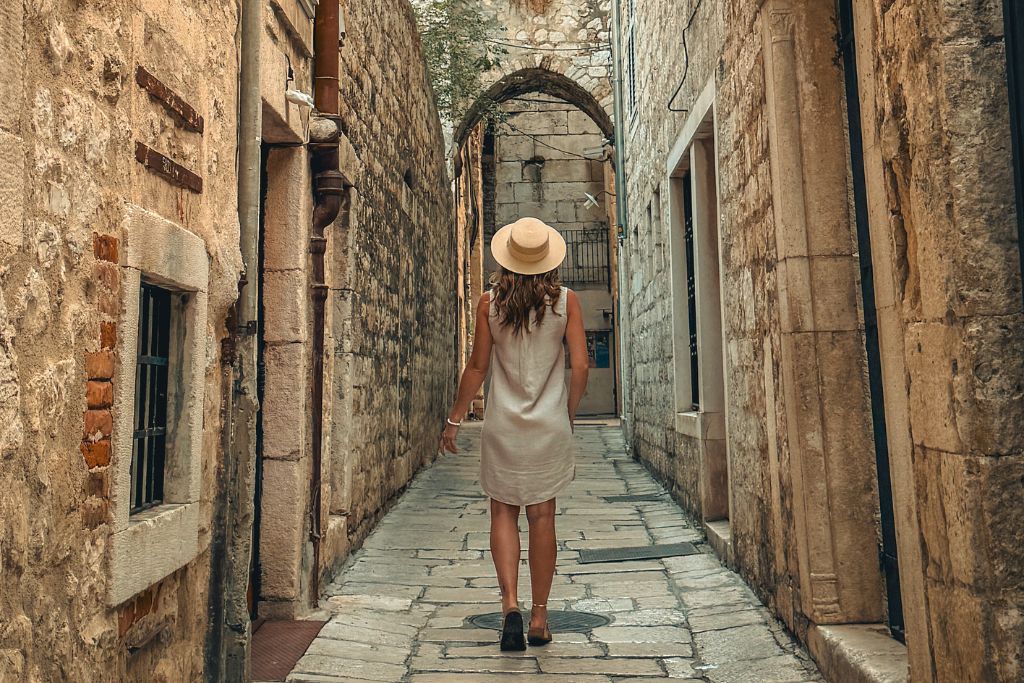 Kate walking down a very narrow cabblestone street with old stone buildings on both sides in Split.