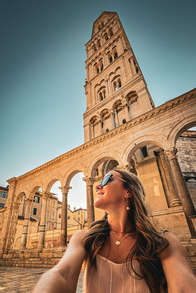 Kate is taking a selfie as the Diocletian Palace Bell tower rises high above her.