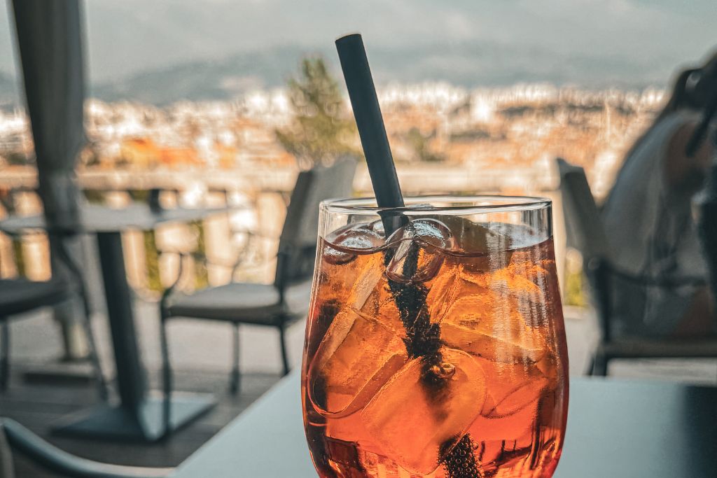 A refreshing Aperol Spritz sits on a terrace café table overlooking Split, with the city's rooftops and harbor softly blurred in the background.