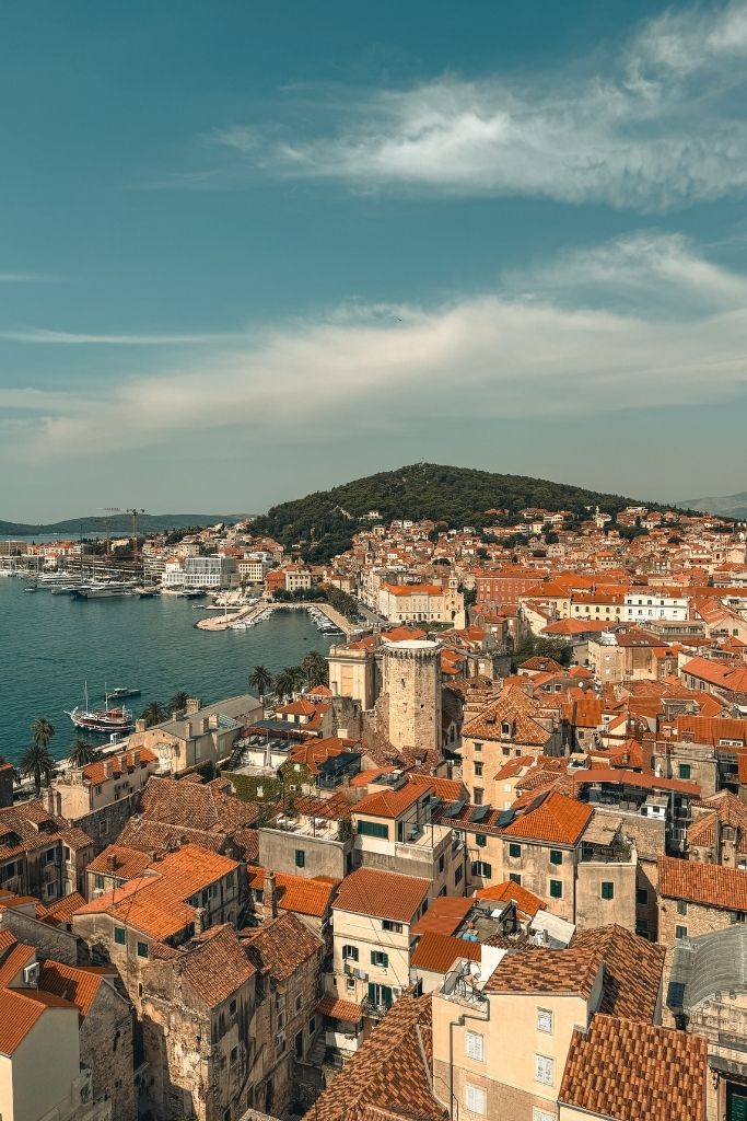 A sweeping view from the Bell Tower of Saint Domnius overlooks Split's Old Town, where terracotta rooftops stretch toward the harbor and Marjan Hill rises in the distance.
