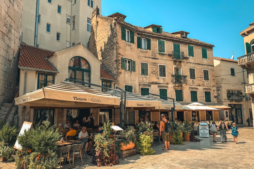 A charming square in Split's Old Town is lined with outdoor cafés and weathered stone buildings, creating the perfect spot to relax and soak up the city's historic atmosphere.