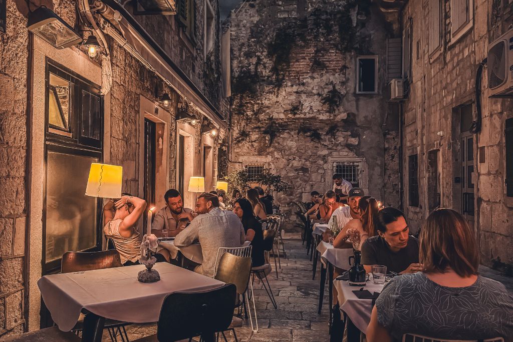 Guests enjoy dinner at candlelit tables tucked inside a narrow stone alleyway in Split's Old Town, creating a cozy atmosphere that feels both romantic and uniquely Croatian.