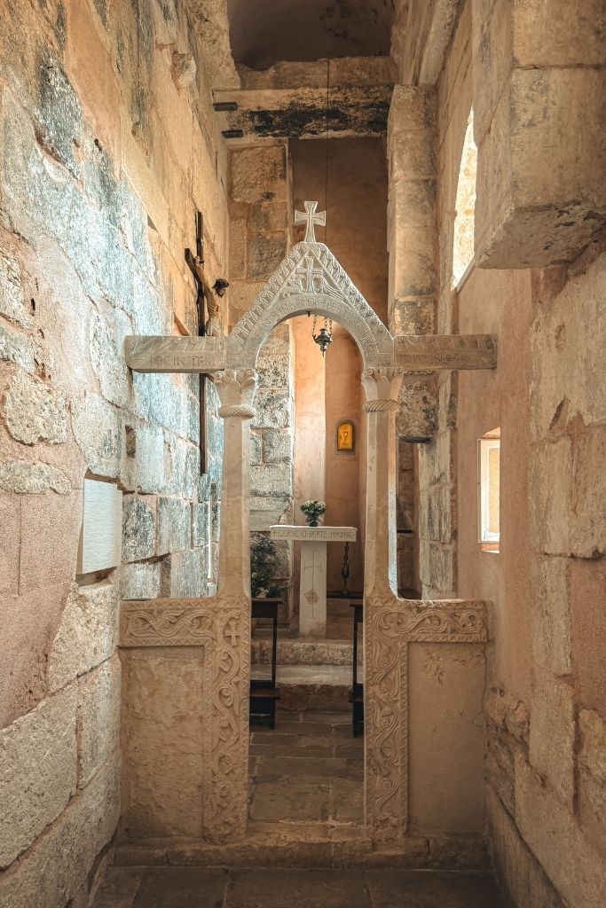 A narrow stone chapel inside Diocletian's Palace features an intricately carved medieval altar screen, weathered walls, and soft light filtering through small windows.