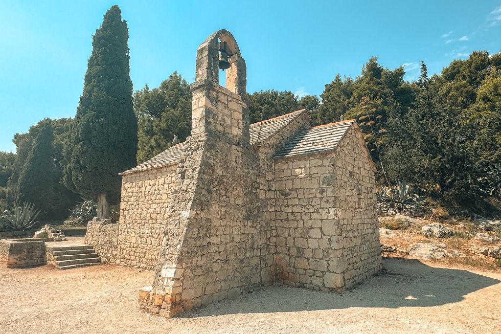 A small historic stone chapel sits among the pine trees on Marjan Hill, surrounded by peaceful woodland and Mediterranean vegetation.