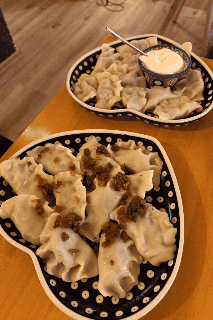Plates of traditional Polish pierogi topped with fried onions and served with sour cream in Krakow, Poland.