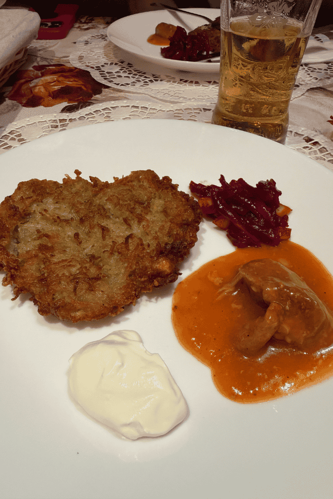 A traditional Polish potato pancake served with creamy meat sauce, sour cream, and shredded beets in Krakow, Poland.