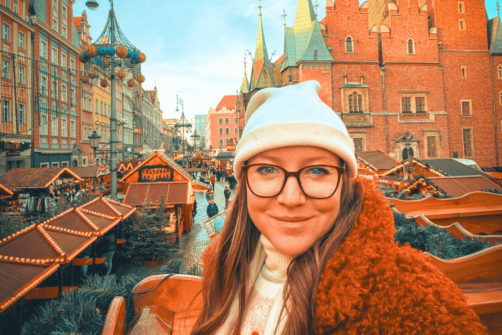 Kate overlooking the Wroclaw Christmas Market, with festive wooden stalls and colorful Old Town architecture in the background.