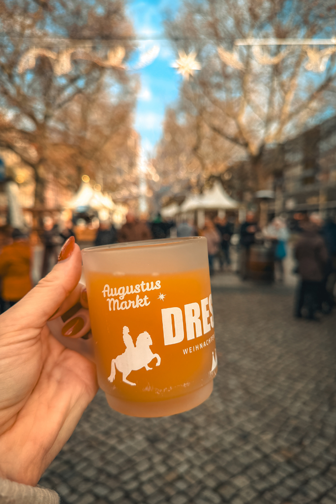 Warming up with a festive drink at Dresden’s Augustusmarkt, surrounded by Christmas stalls and twinkling holiday lights.