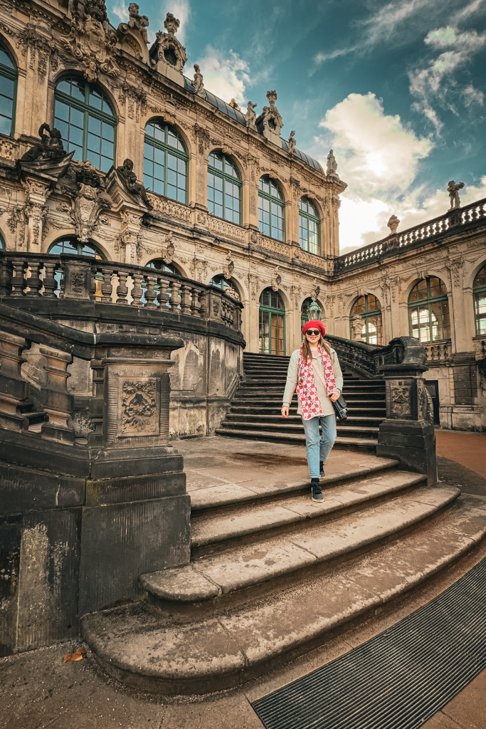 Standing on a grand Baroque staircase with ornate architecture in Dresden’s Zwinger Palace.