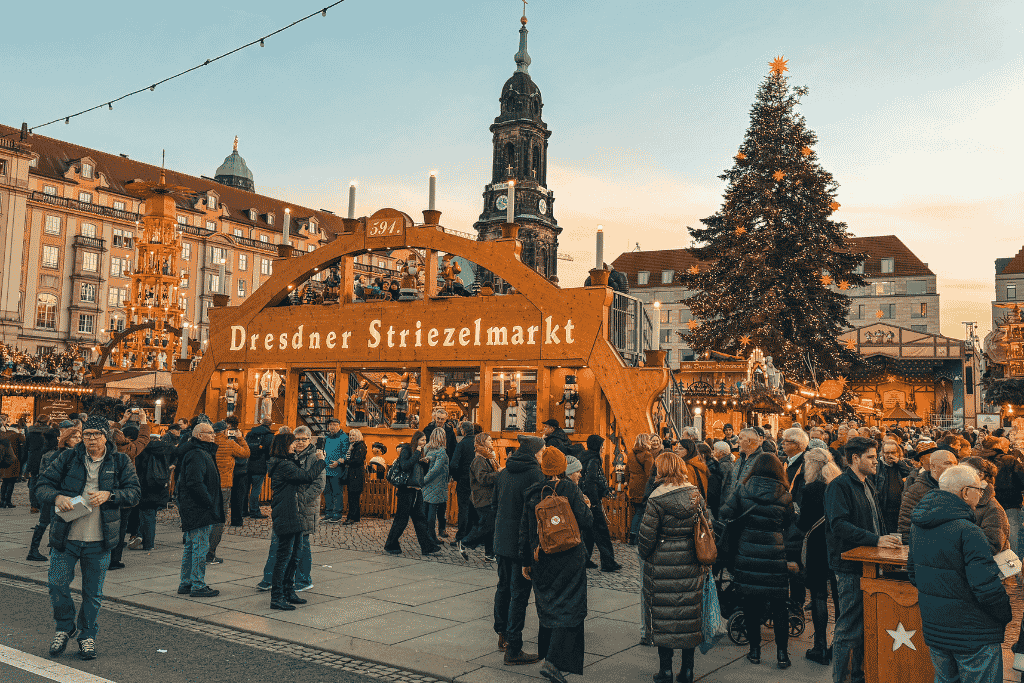 Dresden’s historic Striezelmarkt glows at dusk, with its towering Christmas tree, traditional wooden stalls, and festive crowds filling the heart of the city.