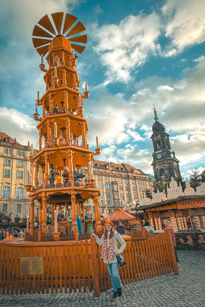 Standing beside the towering Christmas pyramid at Dresden’s historic Striezelmarkt, one of the city’s most iconic symbols of German Christmas market tradition.