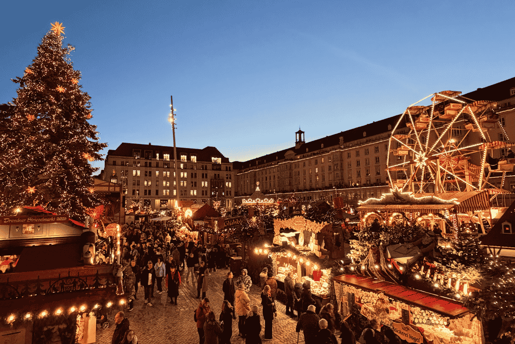 Dresden’s Striezelmarkt comes alive at twilight, when the Christmas tree, Ferris wheel, and rows of festive market stalls glow against the deep blue winter sky.