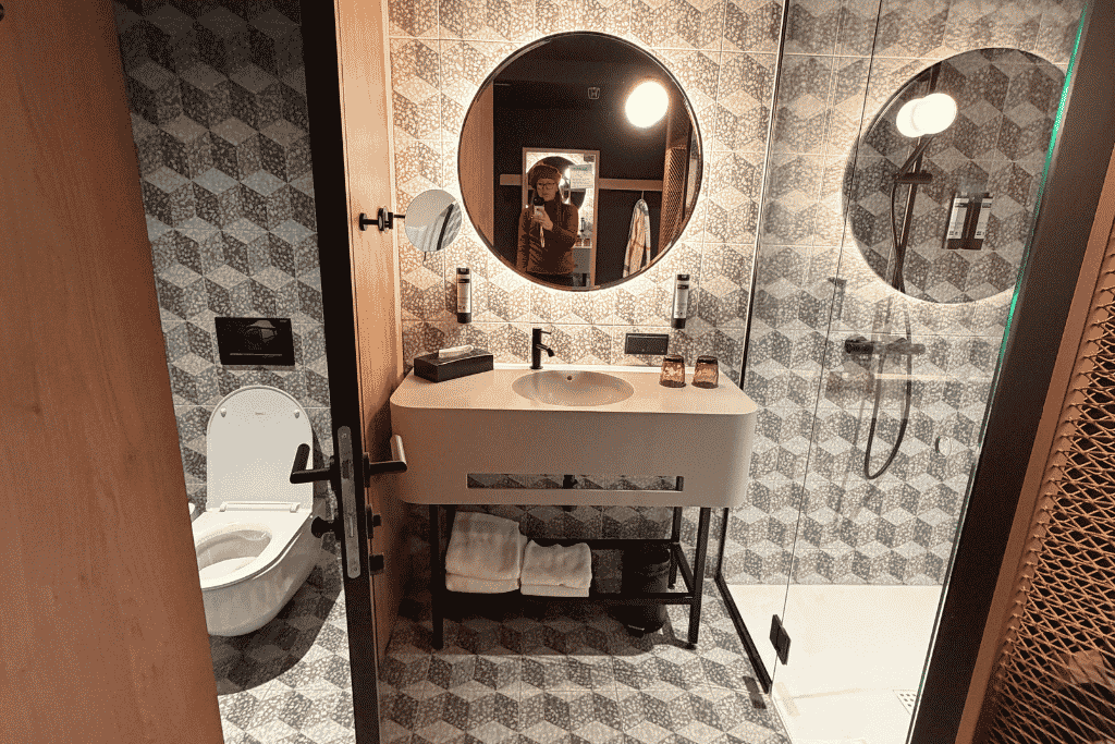 The stylish hotel bathroom features geometric tile, a spacious walk-in shower, and modern finishes.