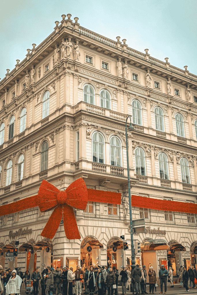 Eggs Benedict with ham and yellow sauce is served at Café Sacher, with a slice of chocolate cake and whipped cream in the background.

A grand historic building is decorated for Christmas with a giant red bow and ribbon as crowds gather along the street below.