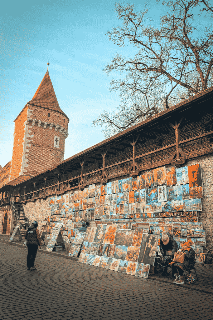 Local artists displaying paintings along Krakow’s historic city walls near St. Florian’s Gate in Old Town.