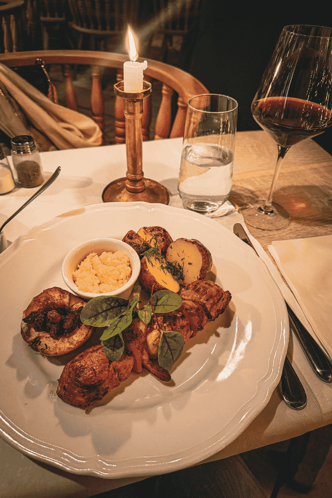 A beautifully plated Polish dinner with roasted meat and potatoes served by candlelight at Pod Aniołami in Krakow.