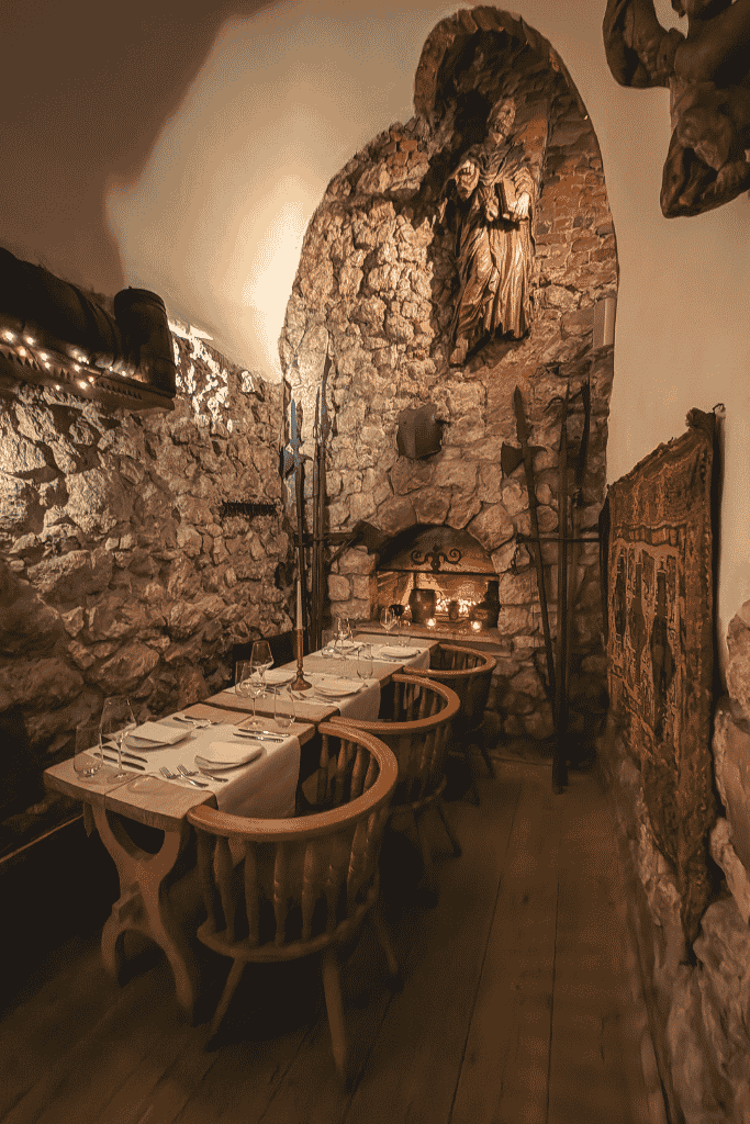 The intimate Gothic cellar dining room at Pod Aniołami in Krakow, with historic stone walls and candlelit tables.