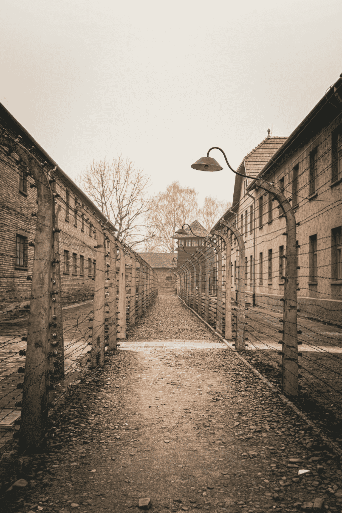Barbed-wire fences and brick barracks line a pathway inside the Auschwitz concentration camp in Poland.