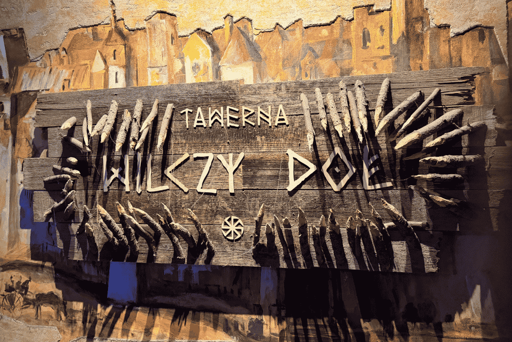 Rustic wooden sign for Tawerna Wilczy Dół, a medieval-themed restaurant in Krakow, Poland.
