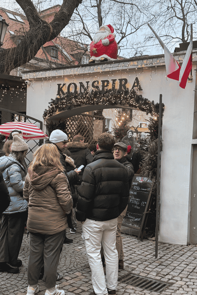 Festively decorated entrance to Konspira restaurant in Wroclaw, Poland, with visitors gathered outside.